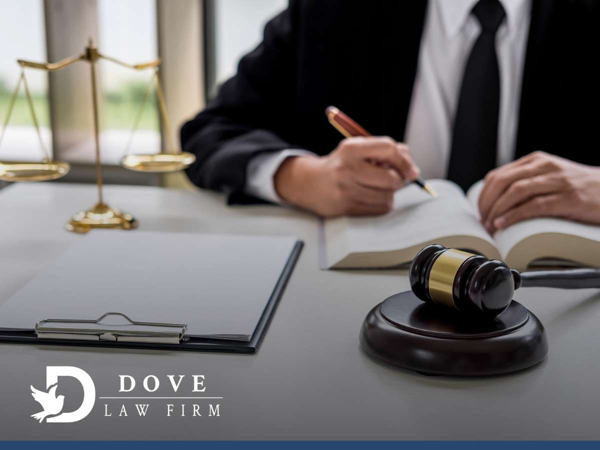 A lawyer at Dove Law Firm writes notes, a gavel, and scales of justice on the table, focusing on defense against bribery charges